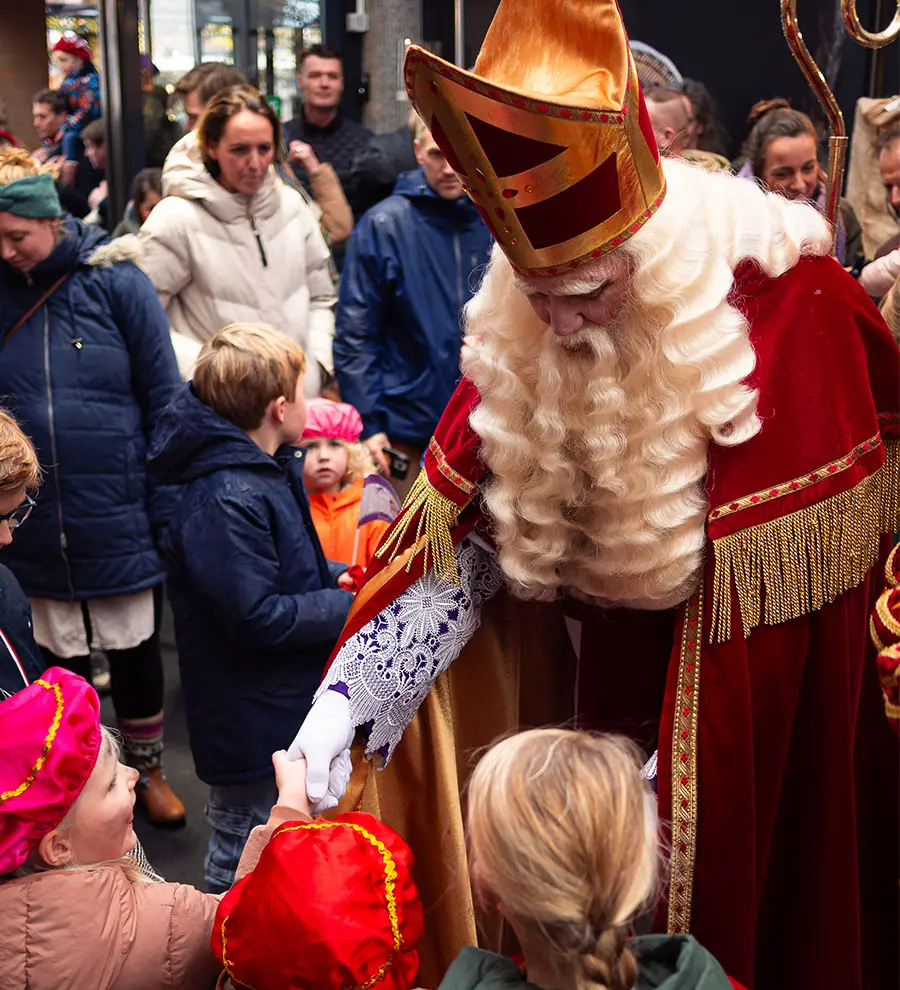 Sinterklaas geeft een kind een hand tijdens de intocht in Heiloo